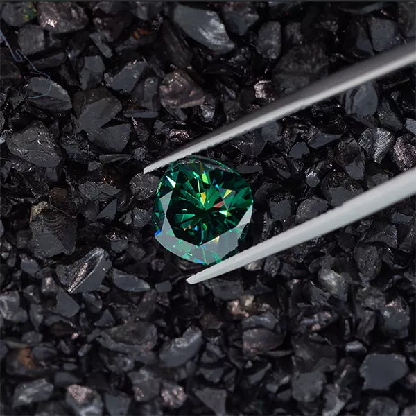 green cushion cut moissanite stone between tweezers on a crushed stone background