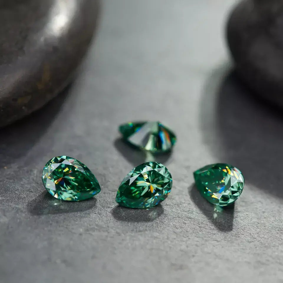 a collection of green pear moissanite stones on stone surface, shallow focus