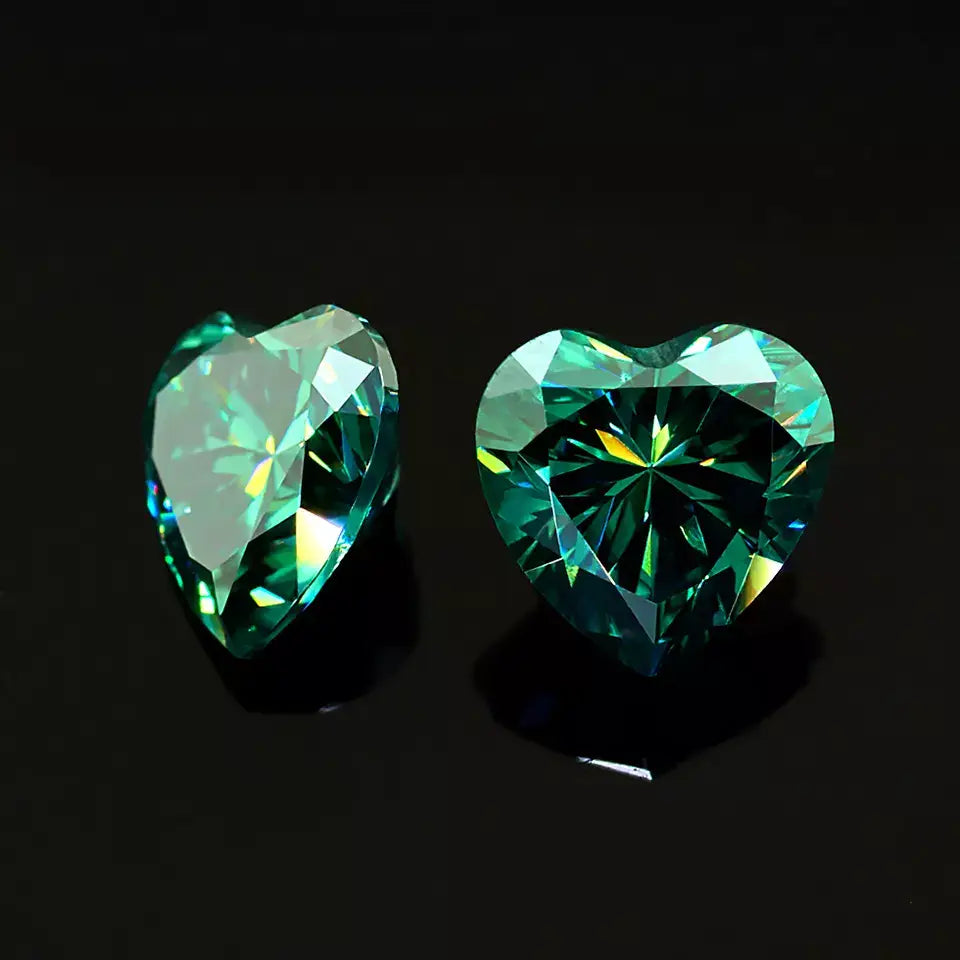 a pair of green heart cut moissanite stones on reflective black background, top and side view