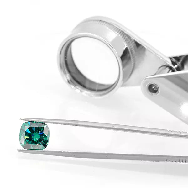 green cushion cut moissanite stone in tweezers on a white background