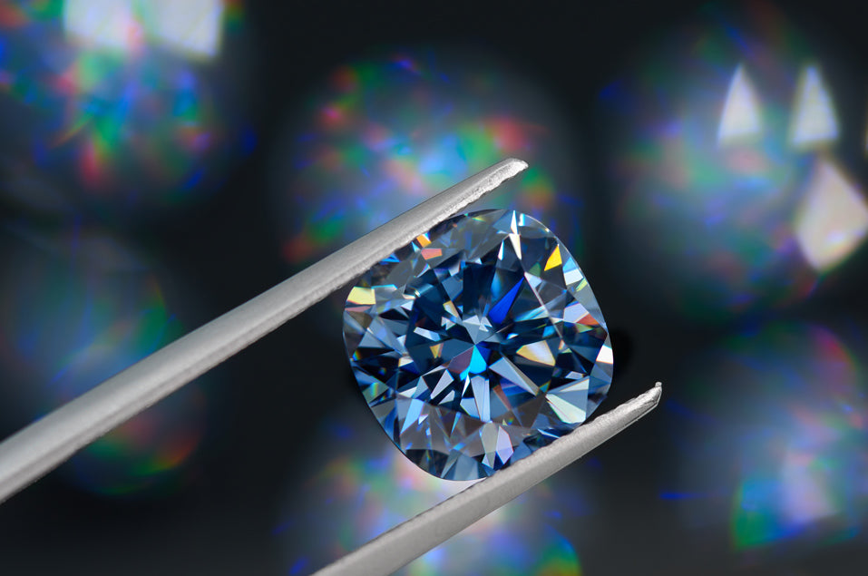 blue cushion cut moissanite stone betweez tweezers, black bokeh background with brilliant reflections