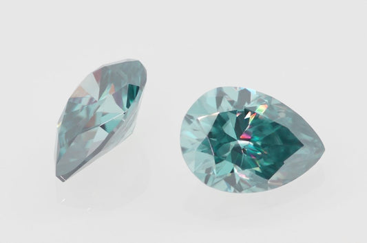cyan pear cut moissanite stone on off white background, top and side view