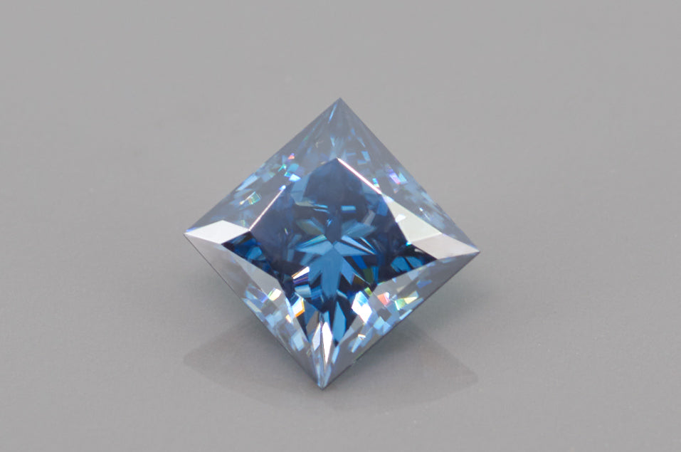 blue princess cut moissanite stone on light grey background