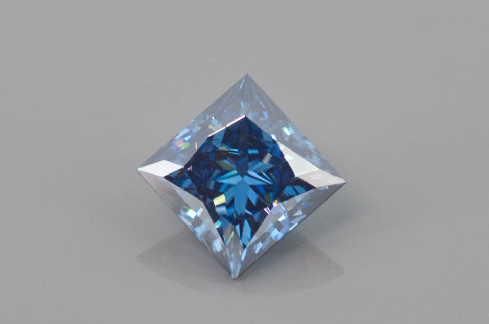 blue princess cut moissanite stone on light grey background