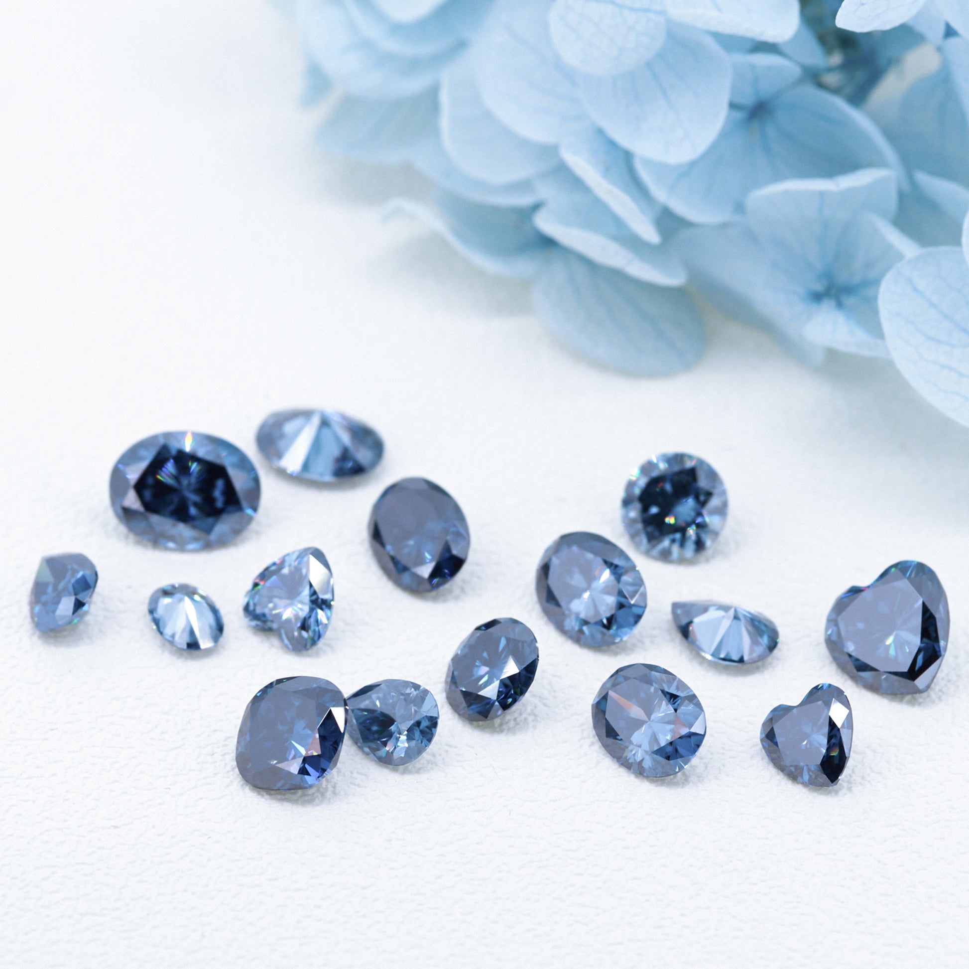 a collection of different cuts of dark blue moissanite stones on white background