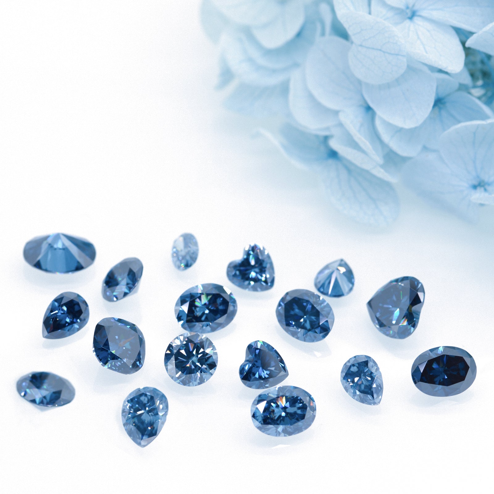 a collection of different cuts of dark blue moissanite stones on white background