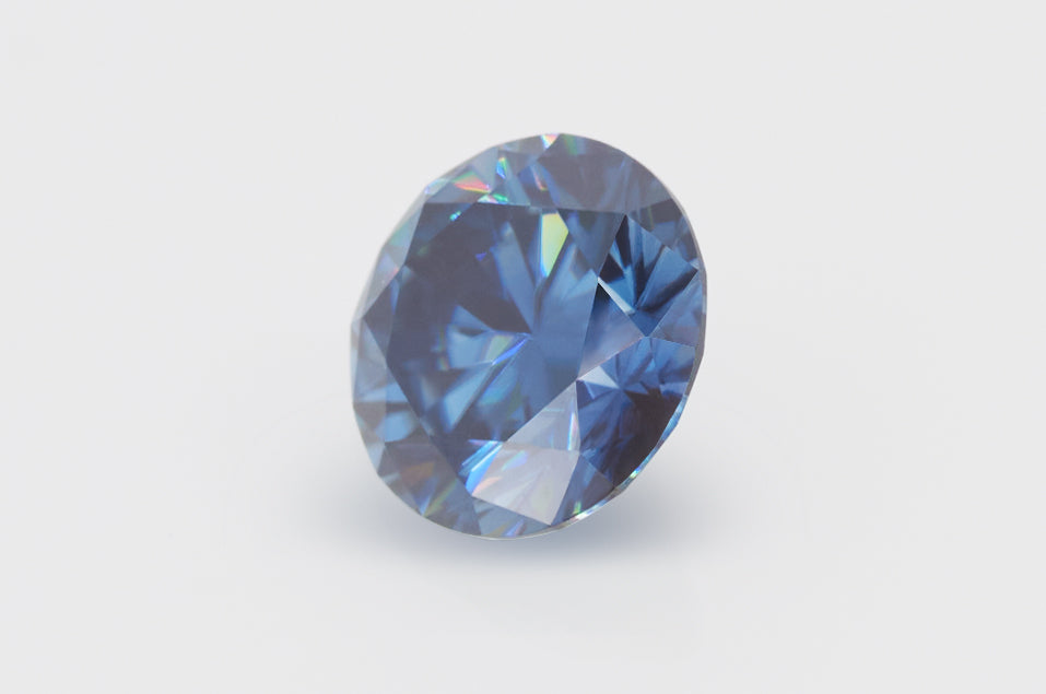 dark blue round cut moissanite stone on light grey background, lying on its side