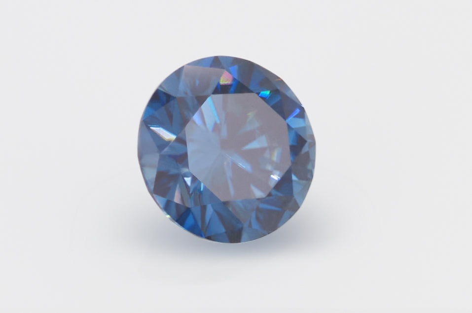 dark blue round cut moissanite stone on light grey background, lying on its side