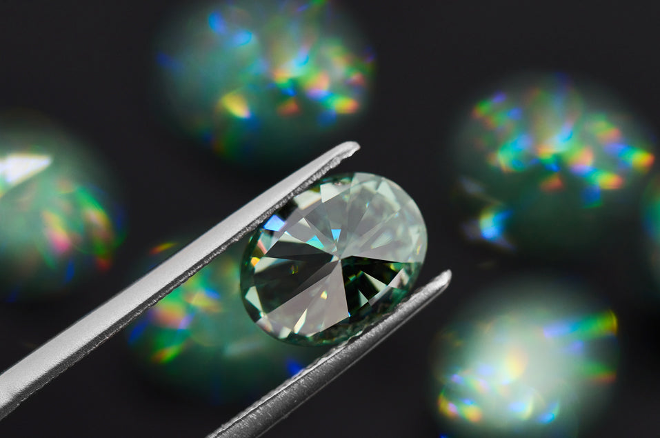 green oval cut moissanite stone on dark bokeh background with several other green stones