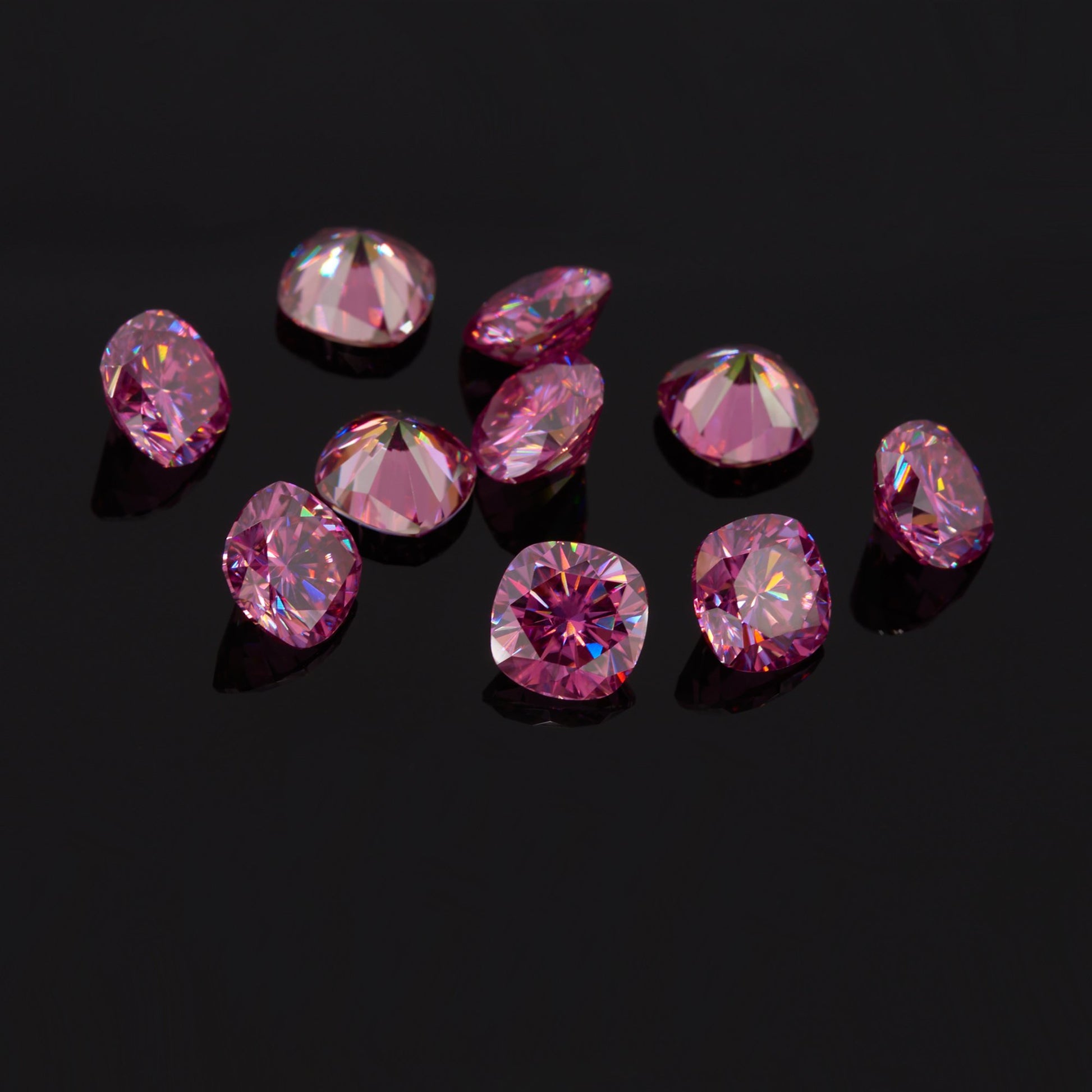 a collection of pink cushion cut moissanite stones on reflective black background