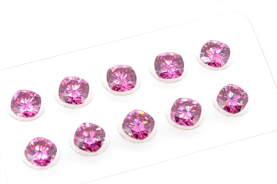 a collection of pink cushion cut moissanite stones in a clear plastic container