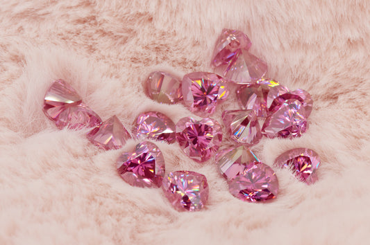 a collection of pink heart cut moissanite stones on light pink fur