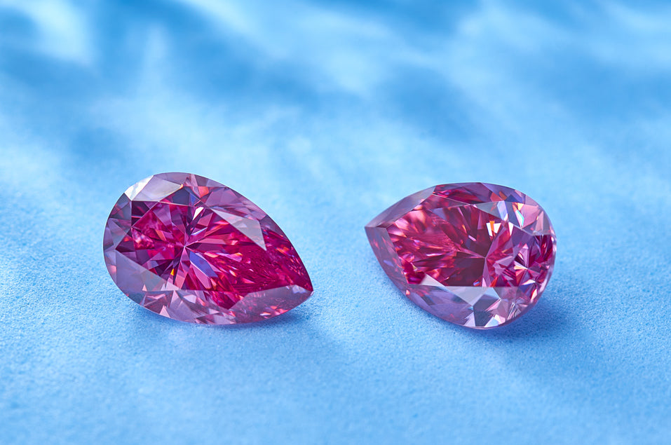 a pair of pink pear cut moissanite stones on baby blue background