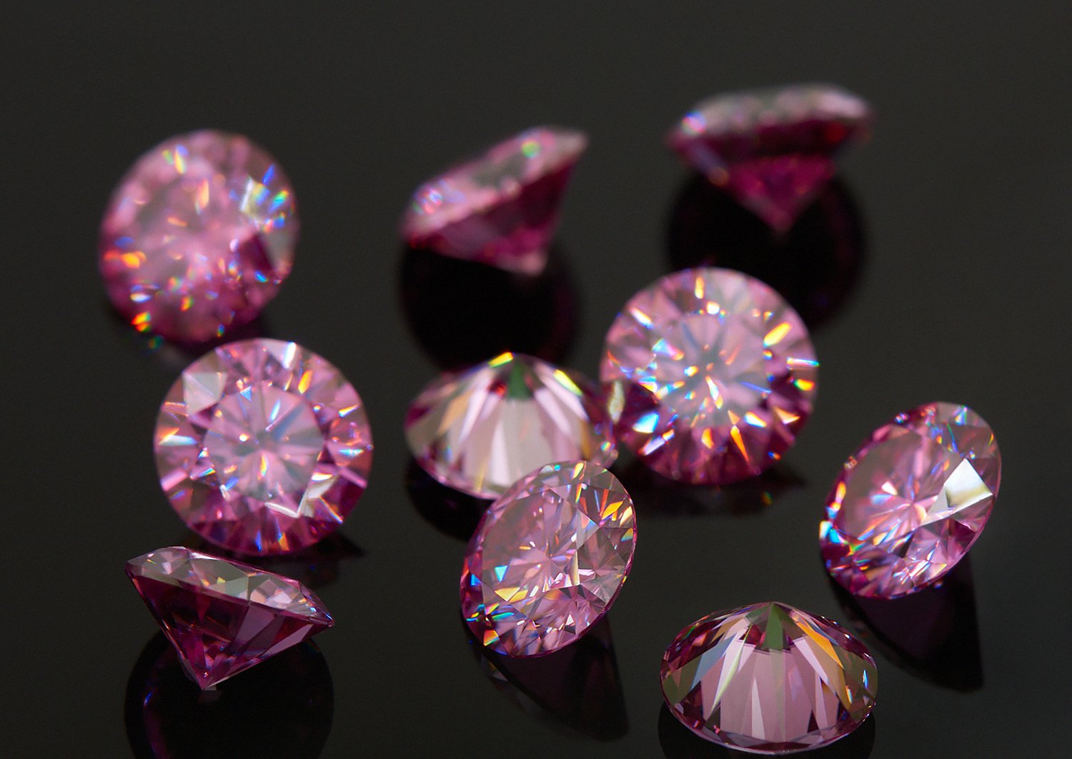 a collection of pink round cut moissanite stones on black background, different sizes