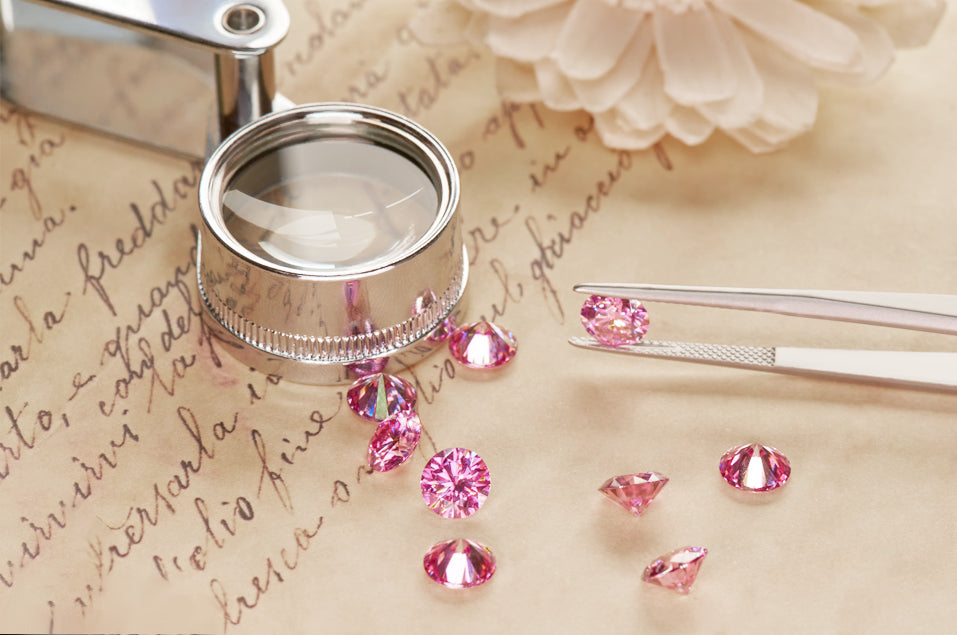 a collection of pink round cut moissanite stones on a parchment with italic writing and magnifying glass