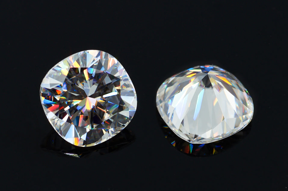 a pair of white cushion cut moissanite stones on black background, brilliant internal reflections