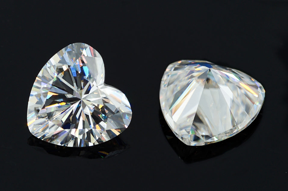 a pair of white heart cut moissanite stones on black background, brilliant internal reflections