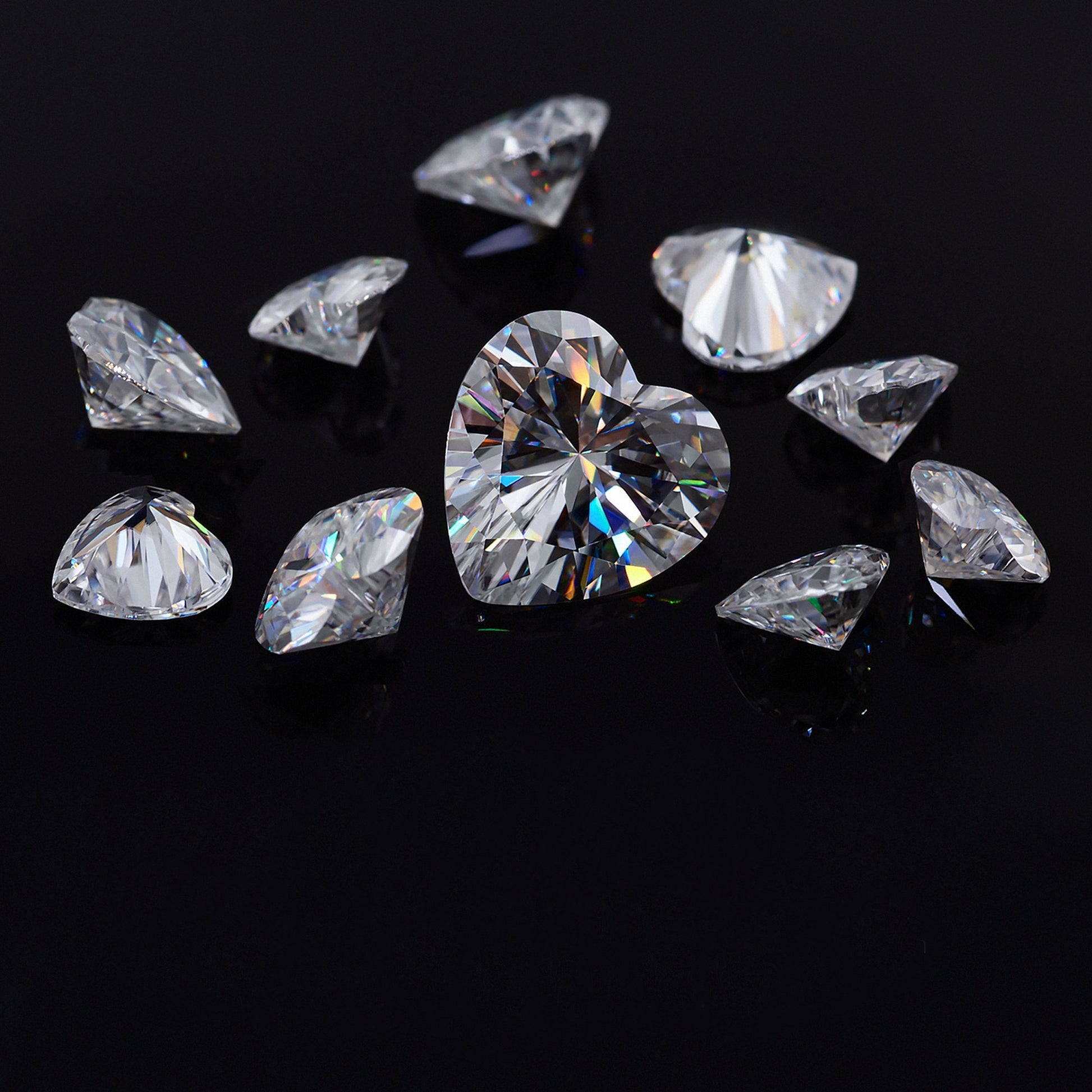 a collection of white heart cut moissanite stones on black background