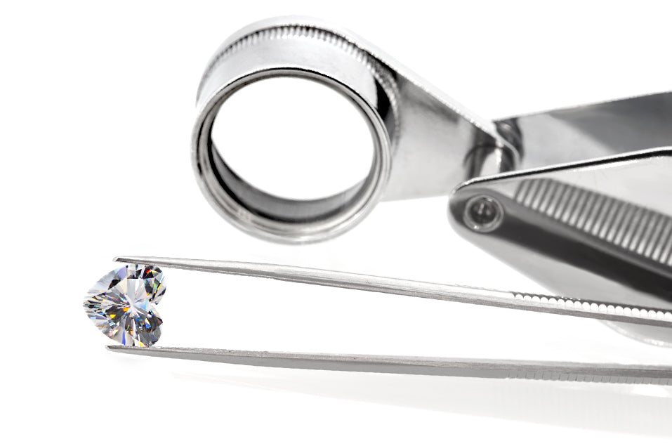 white heart cut moissanite stone between tweezers, beautiful internal reflections