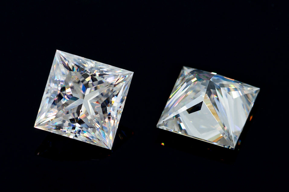 a pair of white princess cut moissanite stones on black background, brilliant internal reflections