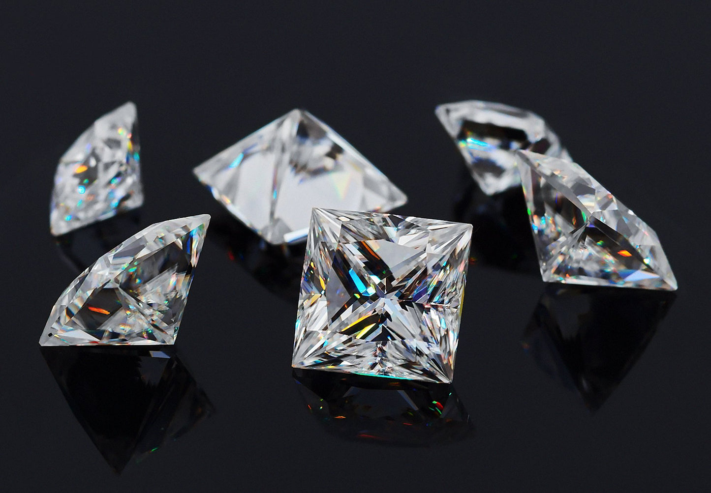 a collection of white princess cut moissanite stones on black background