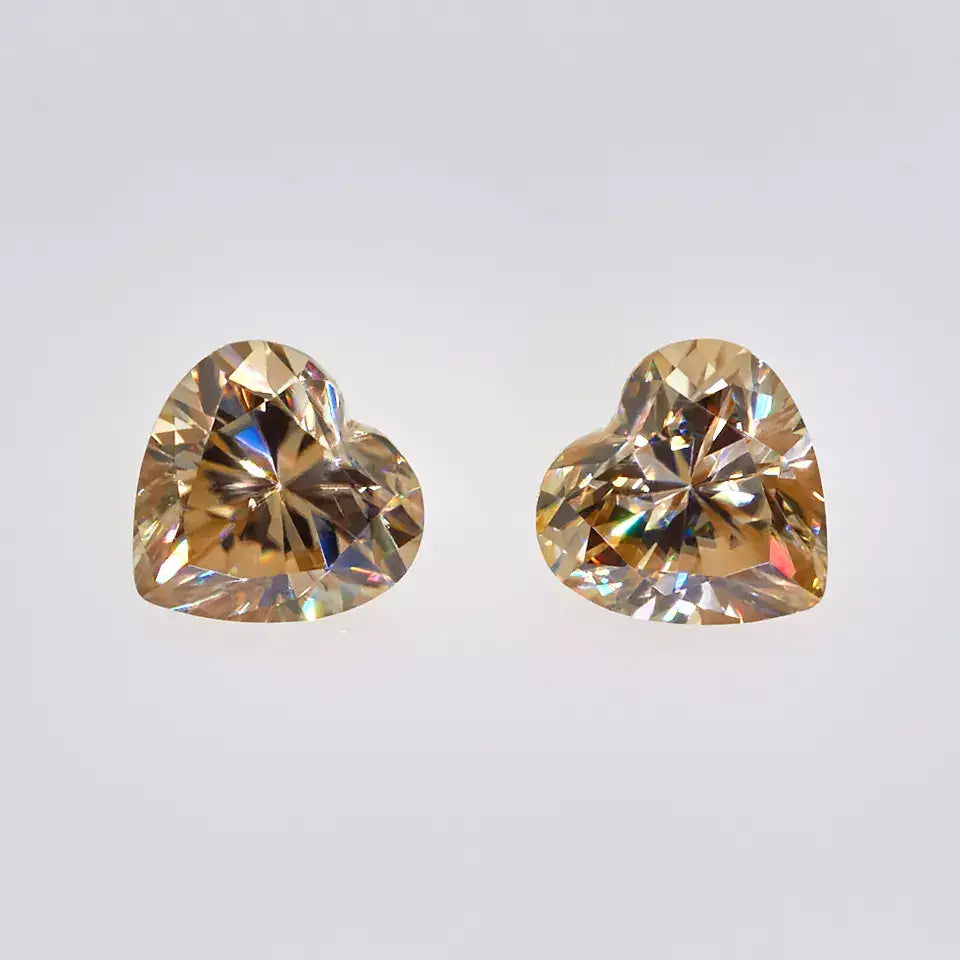 a pair of yellow heart cut moissanite stone on off white background