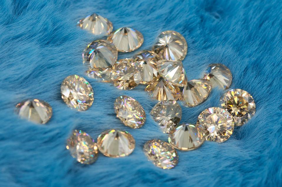 a collection of yellow round cut moissanite stones on blue colored fur