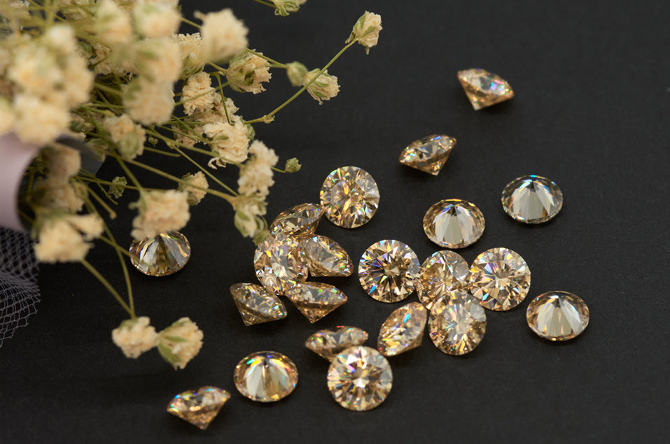 a collection of yellow round cut moissanite stones on black background with dried flowers